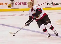 man in white hockey equipment on ice skating with puck