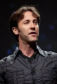 David Eagleman wearing a dark shirt, looking left of camera and appearing to speak