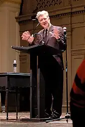 A man standing at a lectern, delivering a speech