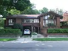 One story house with gabled roofs, wide overhangs, and leaded glass windows..