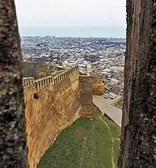 Photograph showing the wall at the Fortifications of Derbent with city buildings in the background