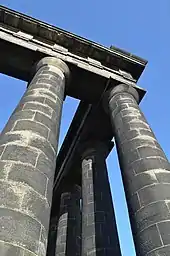 Close-up of blackened columns supporting the entablature