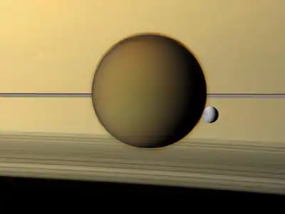 An image of Titan in front Saturn as the smaller moon Dione passes behind its fellow moon. The north pole of Titan is covered by an atmospheric hood which appears as a detached layer at the top of the moon. Imaged on May 21, 2011,  by the Cassini spacecraft.