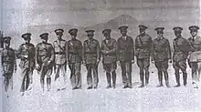 A black-and-white photograph of 12 military officers in early-20th century military dress uniform standing side-by-side and facing the camera