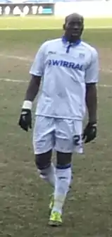 Montserratian professional footballer Donervon Joseph Daniels walking on pitch wearing a  white uniform