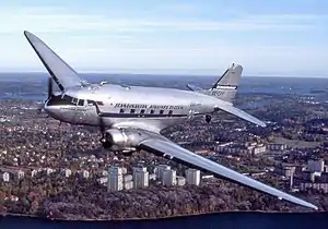 An aircraft in flight with city buildings in background