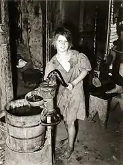 A child drawing water from a hand pump, Oklahoma City, Oklahoma, USA 1939.