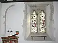 Southeast corner of nave of parish church, showing Perpendicular Gothic window with 1894 glass by Comper & Bucknall and blocked arch of 12th-century window