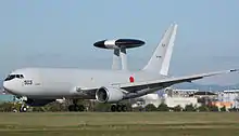 Side view of Japan military reconnaissance aircraft on airport runway, with dorsal mounted sensor pallet