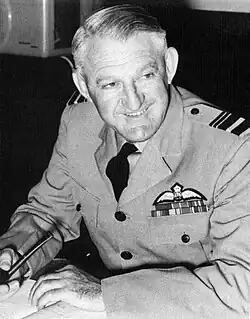  Half-length portrait of Ellis Wackett in military uniform, with pilot's wings on left breast pocket and pipe in left hand