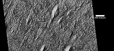 Wide-view of layers in Danielson Crater, as seen by HiRISE under HiWish program. Box shows location of next image. Dark parts of image are dark, basalt sand sitting on level places.