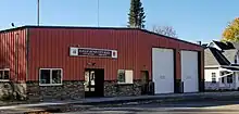 One story brick and wood building with a sign reading "Eagle Bend City Hall, city offices, fire department".