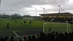 Photograph of players on a football pitch taken from a spectator stand.