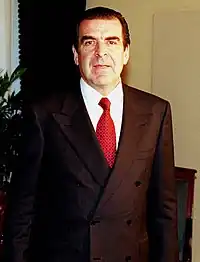 A man wearing a power suit, popular in the European workplace. The suit jacket is double-breasted with large shoulder pads. Photograph taken in 1998.