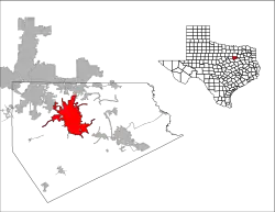 An image of the shape of the state of Texas with lines differentiating the various counties in that state. One of the specific counties is filled in red. A larger image of that specific county sits next to the shape of Texas, with another red shape inside it to demonstrate a specific town within that county.