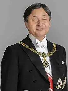 Naruhito wearing a black business suit and a light blue tie