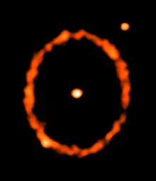 The star is seen at the centre and the ring shows the main belt of the debris disc, which is located at 70 astronomical units from the star. The belt appears elliptical as it is slightly inclined from face-on. In addition to the star, two other point sources appear in the image (one coincident with the belt). These are background galaxies and not part of the epsilon Eridani system.