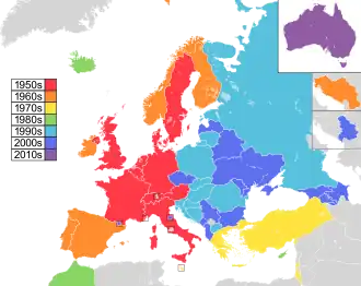 Map of countries in Europe, North Africa and Western Asia, with Australia as an insert in the top-right corner, coloured to indicate the decade in which they first participated in the contest: 1950s in red, 1960s in orange, 1970s in yellow, 1980s in green; 1990s in sky blue; 2000s in blue; and 2010s in purple