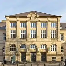 Front façade of a three-story beige stone building