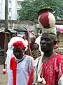 A man carrying a burning pot on his head as part of a procession in a residential area of Lagos. Probably a member of Eyo Iga Etti.