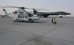 A Qatar Emiri Air Force AW139 and a US Air Force B-1B Lancer on the flight-line at Al Udeid Air Base during 2016.