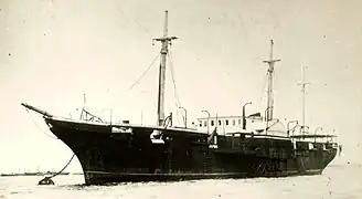 A steamship anchored to a mooring buoy with other ships in the distance