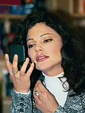 Fran Drescher applying make-up while looking in a compact mirror