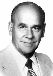 Black and white headshot photograph of Fred Page wearing a light-coloured suit and dark-striped tie