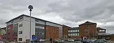 Modern red brick and plaster buildings with a car park in the foreground