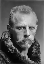  Head of a man with a determined expression, blond hair and moustache, looking straight to the camera