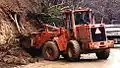 A wheeled front loader tractor equipped with a large bucket elevated by hydraulic rams.