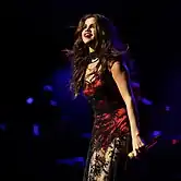 Selena Gomez looking into an arena's crowd while performing.