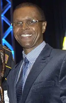 Gale Sayers poses for a picture while holding a trophy.