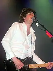 A man playing a guitar and singing into a mic.