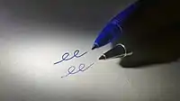 Picture of writing tips of a gel pen and a ballpoint pen lying on a piece of paper next to lines created by each pen.