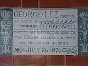 A tablet formed of six standard sized tiles, bordered by green flowers in the style of the Arts and Crafts movement