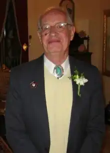 A colour photograph of a balding and grey haired man facing the camera