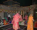 Women in veil performing folk dance at wedding.