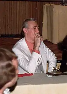 Kane seated at a table, smiling