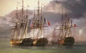 Four ships lie clustered together in shallow water under the shadow of a mountain.