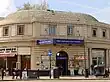 A beige-bricked building with a blue sign reading "GREAT PORTLAND STREET STATION" in white letters all under a blue sky with white clouds