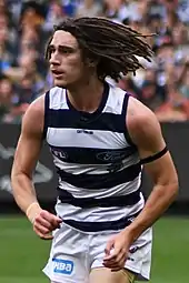 Male athlete with dreadlocks playing in an Australian rules football game