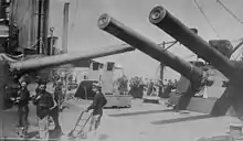 The crowded midships area of HMS Indomitable dominated by the masses of the 12-inch guns of 'P' and 'Q' turrets, each of which is trained across the deck