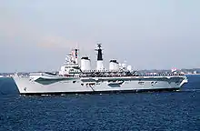 Side view of a small aircraft carrier with a ski-jump ramp underway