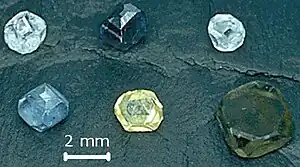 Six non-faceted diamond crystals of 2–3 mm (0.079–0.118 in) size; they are yellow, green-yellow, green-blue, light-blue, light-blue and dark blue.