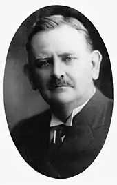 Black and white photograph of man with moustache in suit