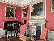 A richly-furnished antechamber to the adjacent dining room, it contains paintings, porcelain jars, silk damask wall hangings and an elaborate cabinet on a stand.