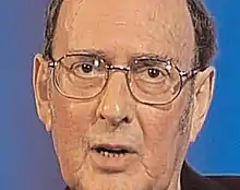 head shot of bespectacled ageing man talking