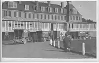 Black-and-white photo of old ambulances next to a building