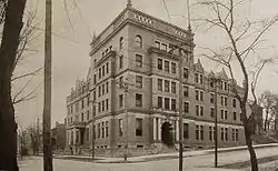 A 5-story stone building built on a street corner, with two entrances